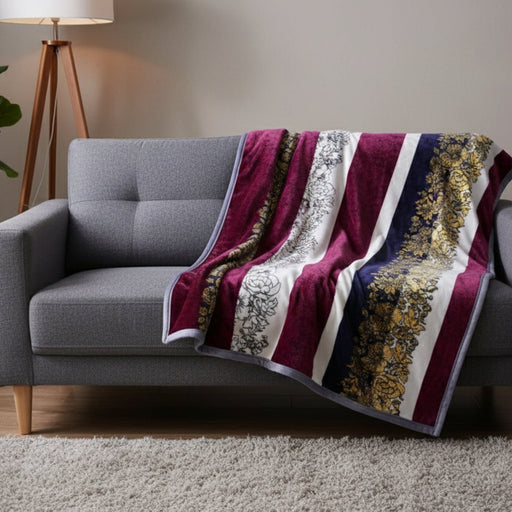 Gray sofa with a decorative burgundy blanket featuring gold and white patterns.