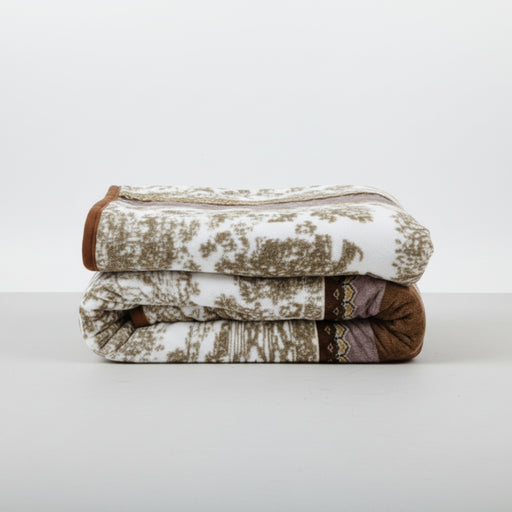 Stack of patterned mink blankets on a white surface with a white background