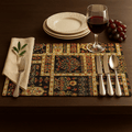 persian Dining table setting with a decorative placemat, wine glass, plates, cutlery, and grapes.