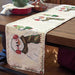 Decorative table runner with snowman design on a wooden table.