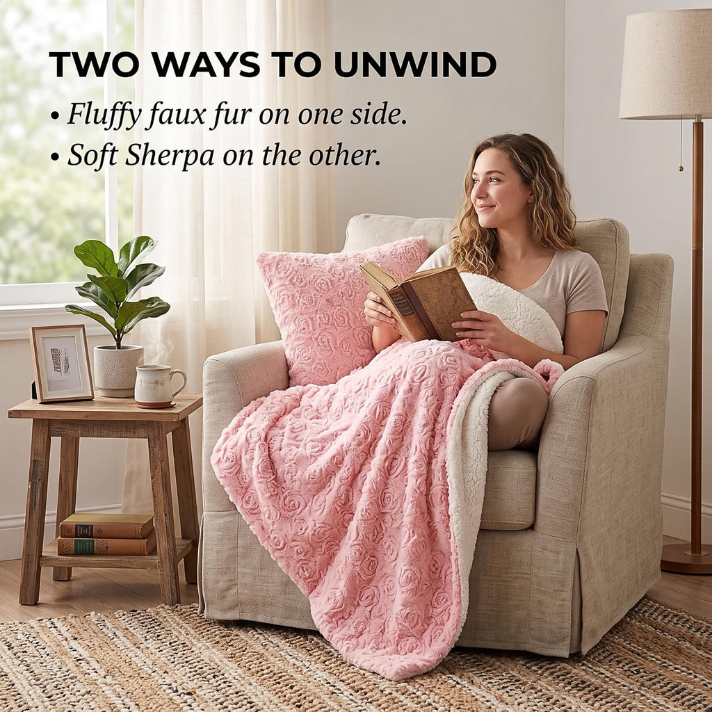 A woman relaxes in a beige armchair reading a book, wrapped in a pink faux-fur throw blanket with a white sherpa reverse side. Text at the top reads 'TWO WAYS TO UNWIND' with bullet points describing the blanket's dual-sided texture.