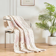 DaDalogy Cotton Patchwork Throw Blanket draped on a chair, featuring blush pink and cream floral patterns.