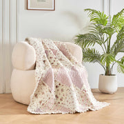 DaDalogy Cotton Patchwork Throw Blanket on a cozy chair, featuring floral designs in blush pink and cream.