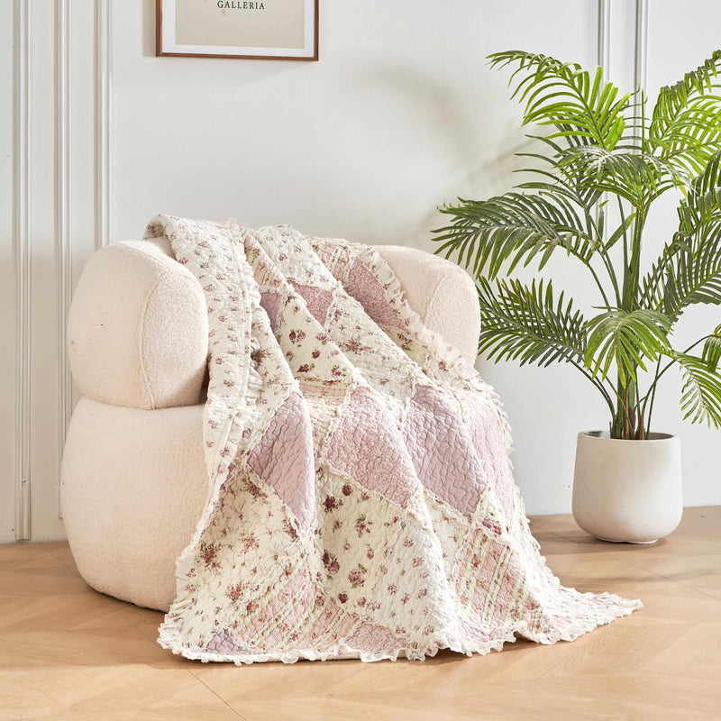 DaDalogy Cotton Patchwork Throw Blanket on a cozy chair, featuring floral designs in blush pink and cream.