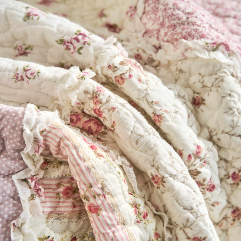 Close-up of DaDalogy Floral Cottage Patchwork Throw Blanket with pink and cream ruffles and botanical floral designs.