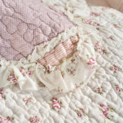 Close-up of DaDalogy Cotton Patchwork Throw Blanket featuring floral designs and ruffle details in blush pink and cream.