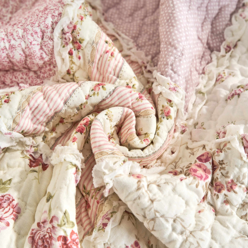 Close-up of DaDalogy Cotton Patchwork Throw Blanket in floral design with blush pink and cream ruffles, showcasing vintage charm.