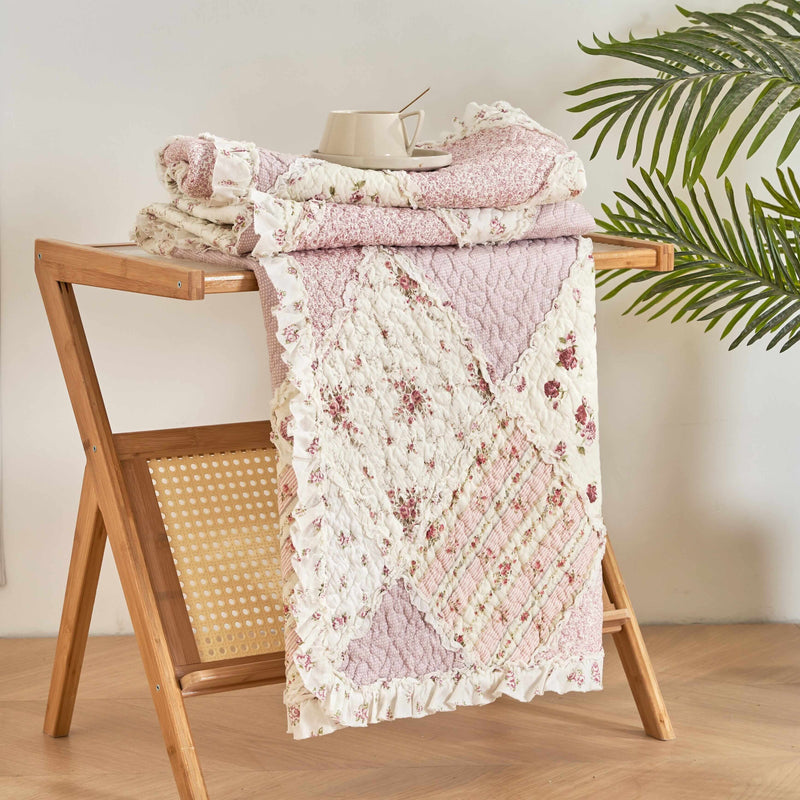 DaDalogy Cotton Patchwork Throw Blanket in blush pink and cream on a wooden rack, showcasing shabby chic floral design.