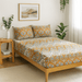 Bed with patterned bedding in a bedroom setting with plants and a side table.