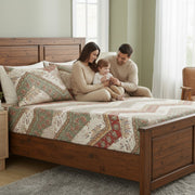 Family sitting on a wooden bed with patterned bedding in a bedroom with a nice fitted sheet.