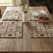 Dining table set with patterned placemats, a vase of flowers, and a bowl of fruit.