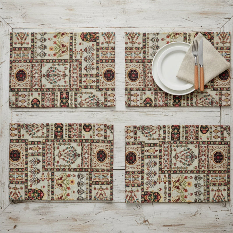 Four patterned placemats on a wooden surface with a plate and cutlery.