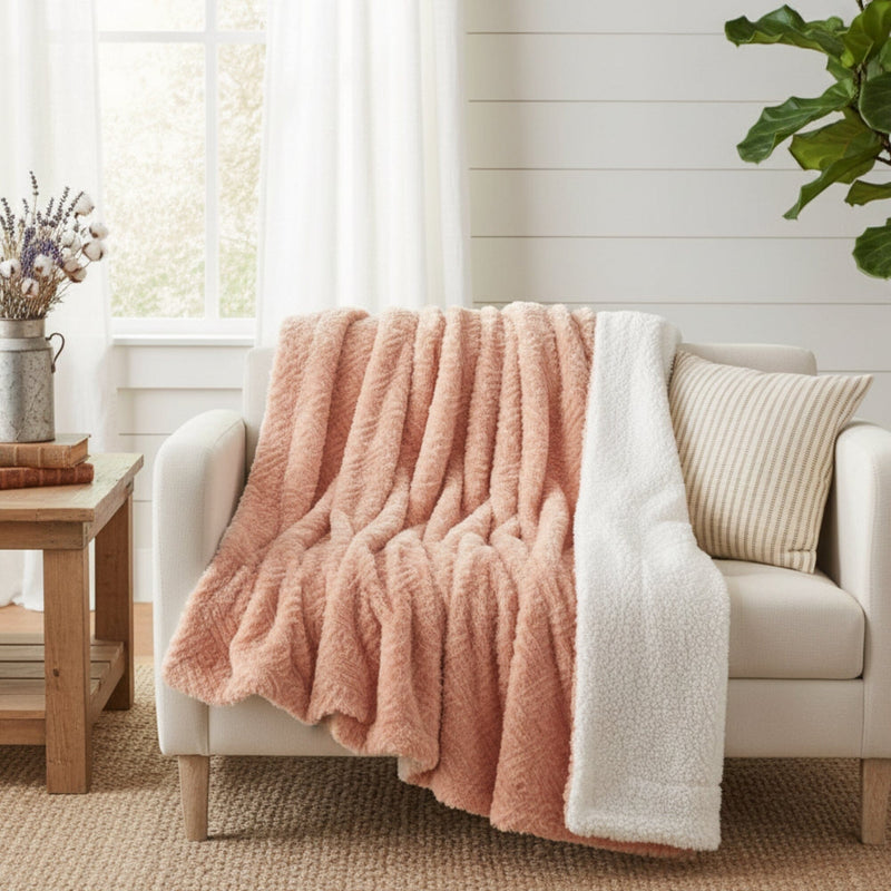 Coral peach sherpa throw blanket with geometric herringbone design draped over beige sofa