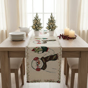 Dining table set with a snowman-themed table runner, candles, and small Christmas trees.