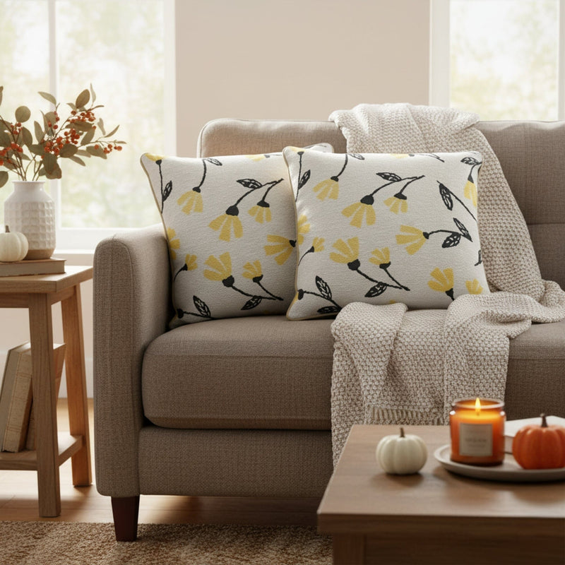 Beige sofa with floral-patterned pillows, a candle, and pumpkins in a cozy living room.