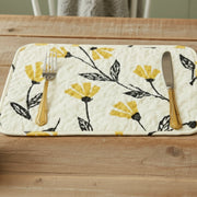 Quilted placemat floral pattern and fall decor and cutlery on a wooden surface