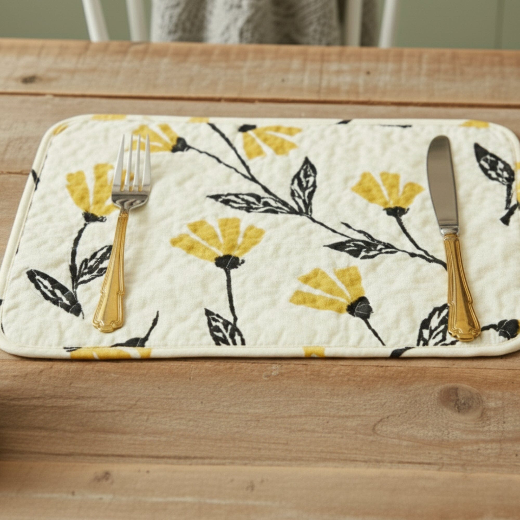 Quilted placemat floral pattern and fall decor and cutlery on a wooden surface