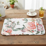 Floral placemat on a wooden table with cutlery and a cup of tea.
