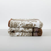 Stack of patterned mink blankets on a white surface with a white background