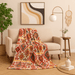 Decorative blanket on a chair in a living room with a plant, lamp, and wall art. aztec blanket